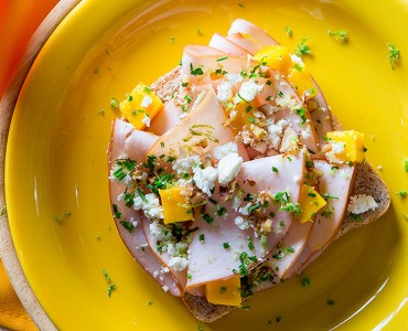 Sanduíche aberto de peru, gremolata, manga e nozes